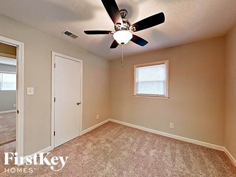the master bedroom has a ceiling fan and a door to the bathroom