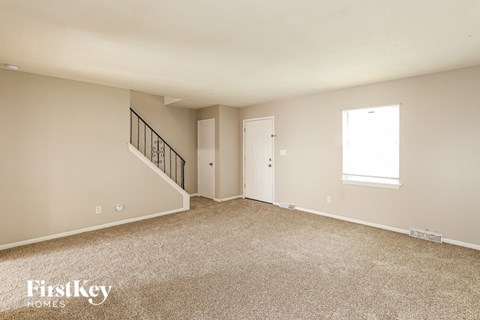 A spacious empty room with a staircase and two doors.