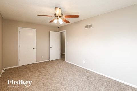 A bedroom with a ceiling fan and two closets.