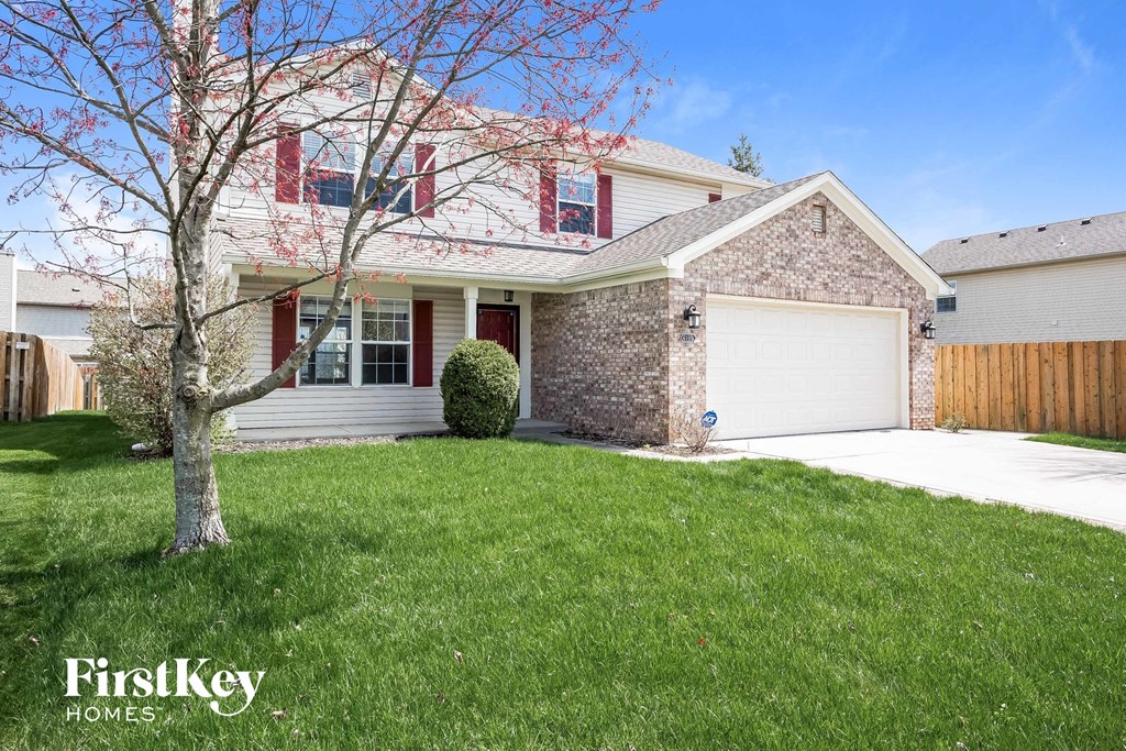 a home with a lawn and a tree in front of it