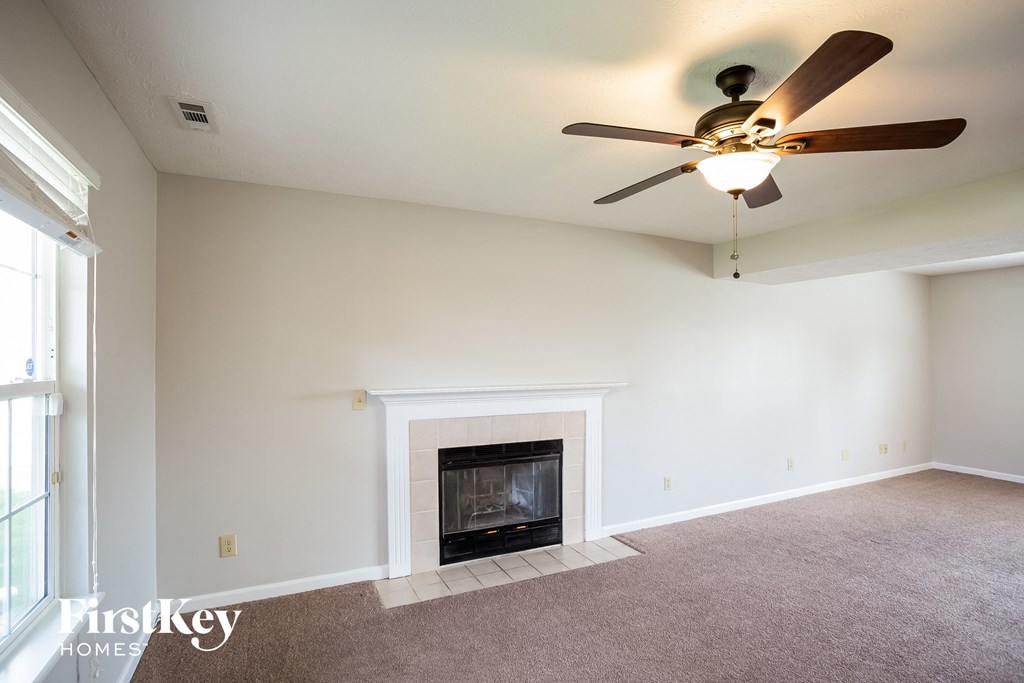 a living room with a fireplace and a ceiling fan