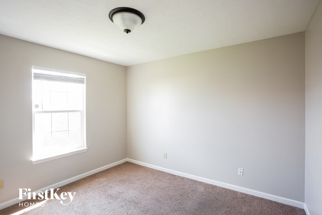 a bedroom with white walls and a window and carpet
