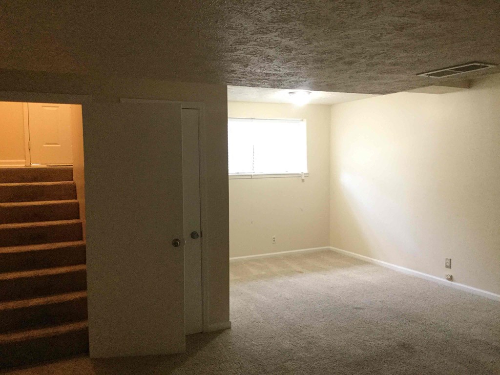 a room with a carpeted floor and white walls and a window