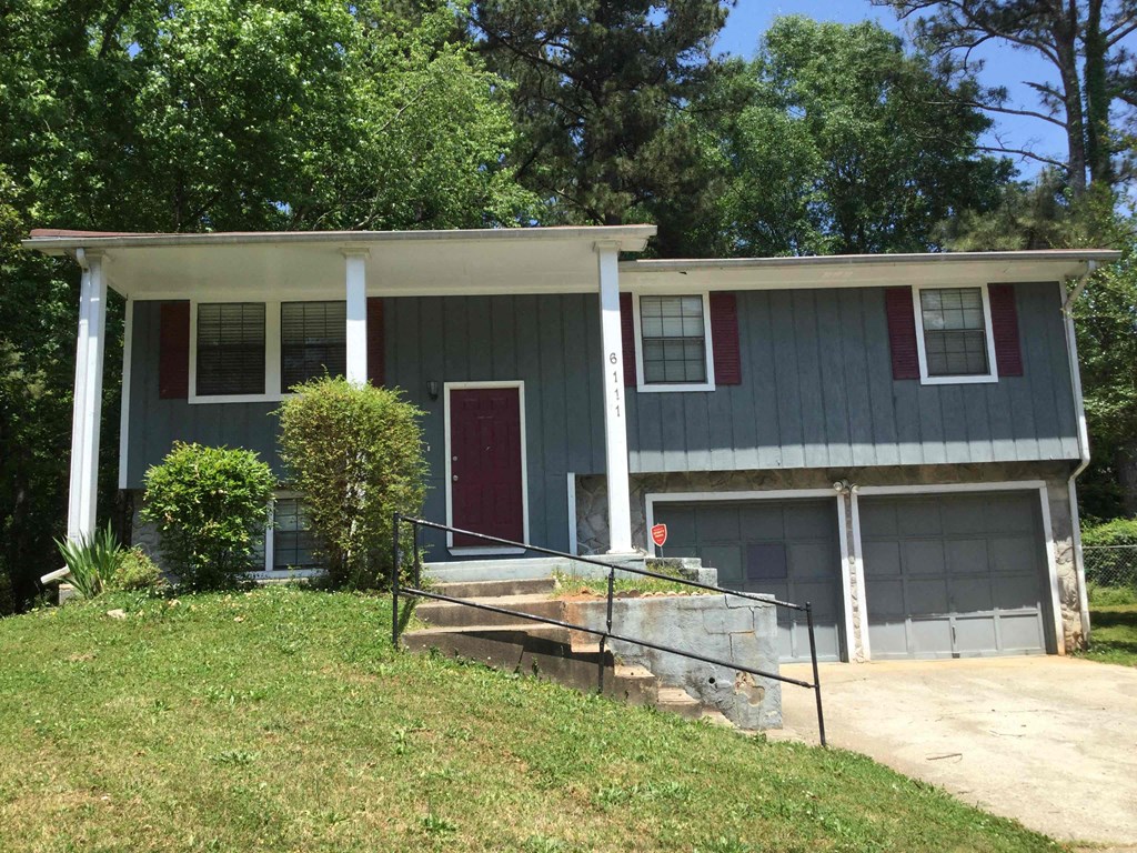 the front of a house with a porch and two garage doors