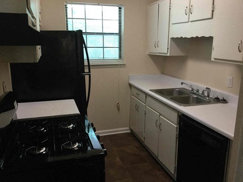 a kitchen with white cabinets and a black stove and sink