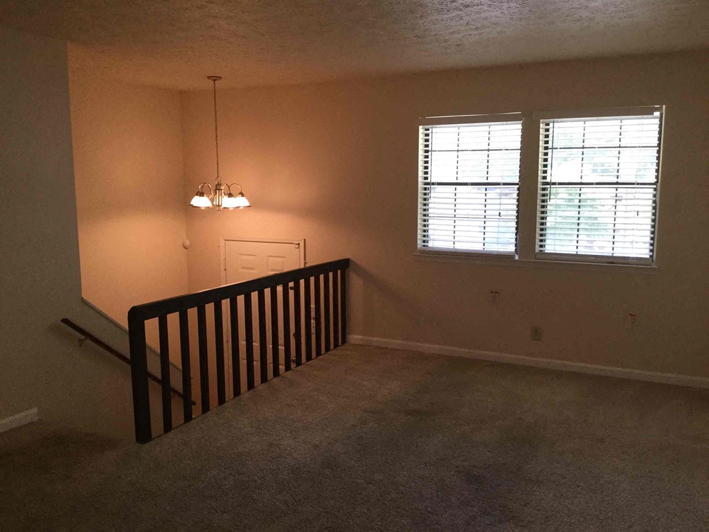 an empty living room with a staircase and a window