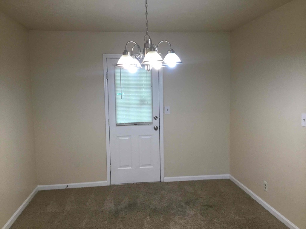 an empty living room with a white door and three lights