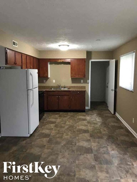 A kitchen with a white fridge and brown cabinets.