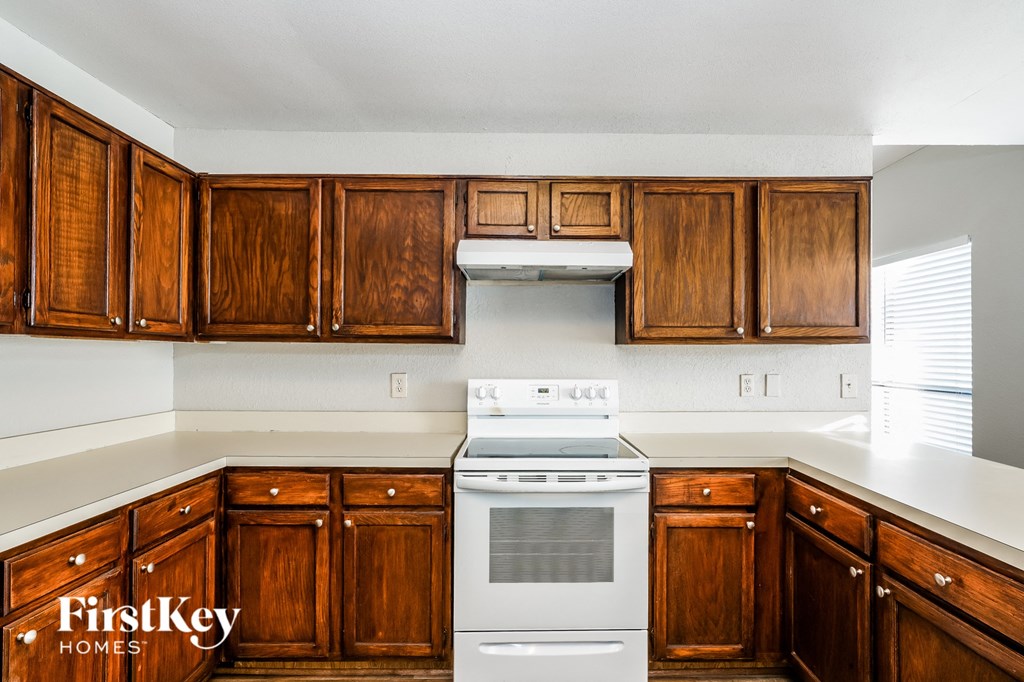 A kitchen with wooden cabinets and a white stove top oven.