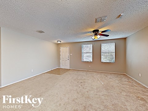 an empty living room with a ceiling fan and a door
