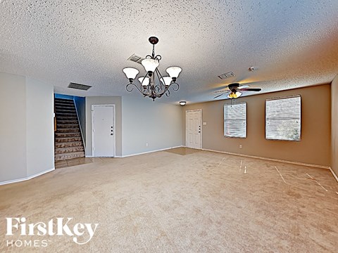 an empty living room with a ceiling fan and a chandelier
