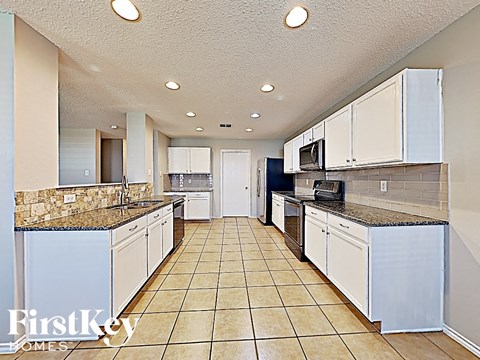 a large kitchen with white cabinets and counter tops