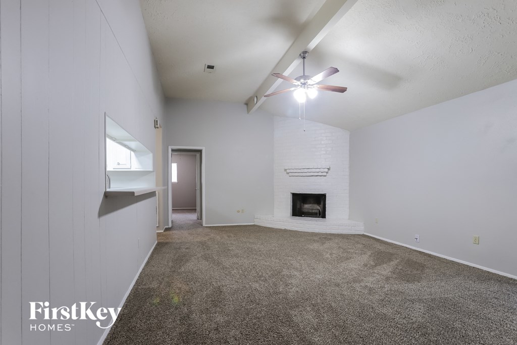 an empty living room with a ceiling fan and a fireplace
