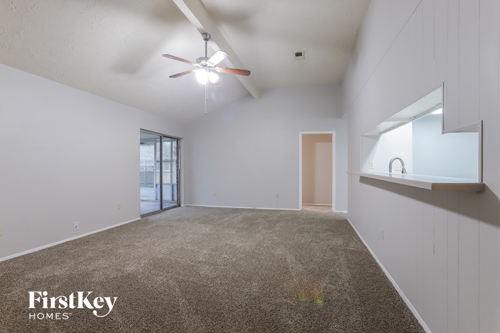 the living room with carpet and a ceiling fan