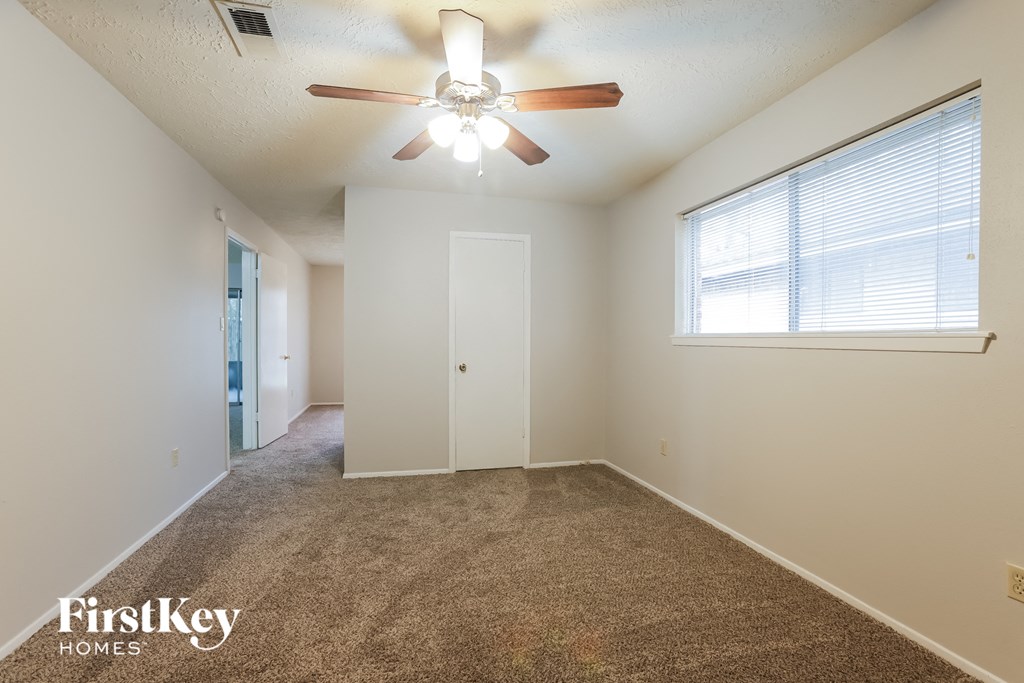 an empty room with a ceiling fan and a window