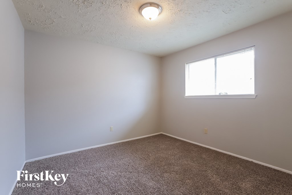 a bedroom with white walls and a window