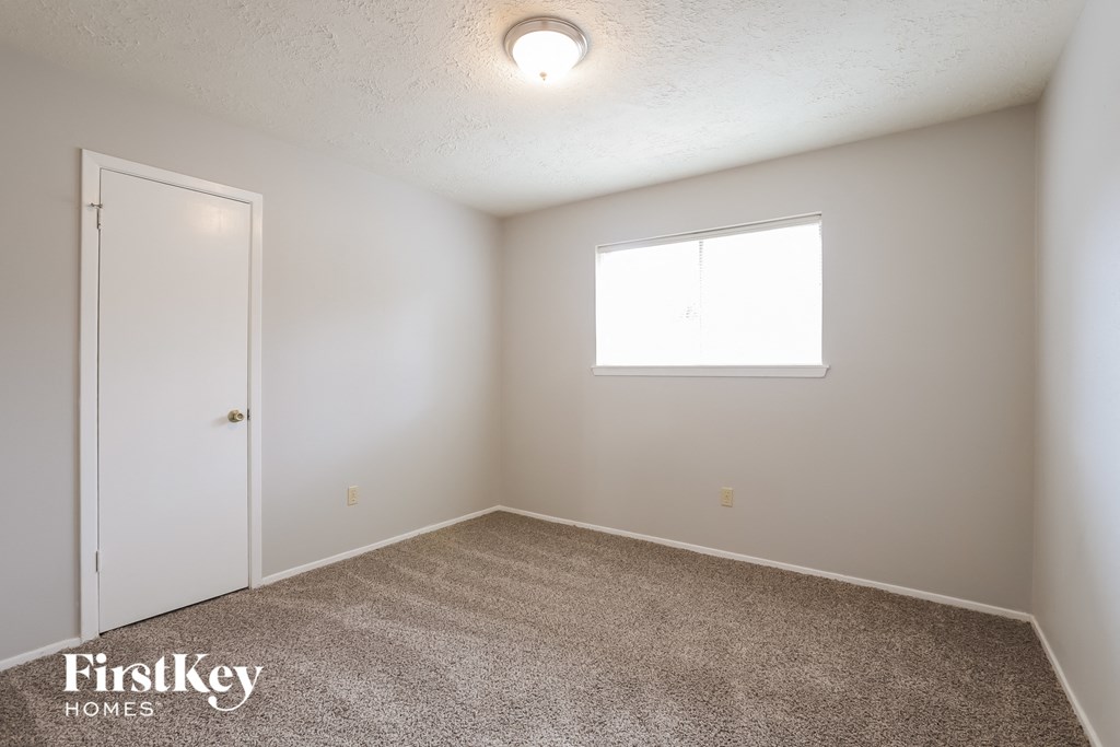 a bedroom with white walls and a white door and a window