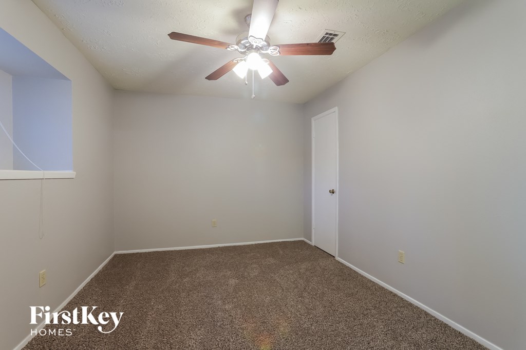 a bedroom with a ceiling fan and a carpet