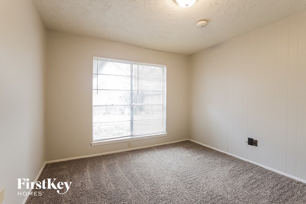 a bedroom with a large window and carpeting