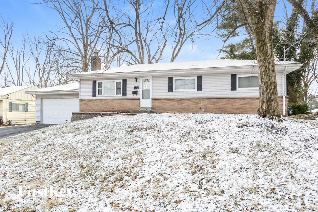 A house with a white garage door and a brown tree in front.
