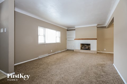 A spacious room with a fireplace and a window.