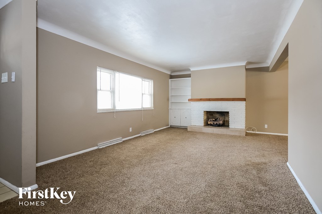 A spacious room with a fireplace and a window.