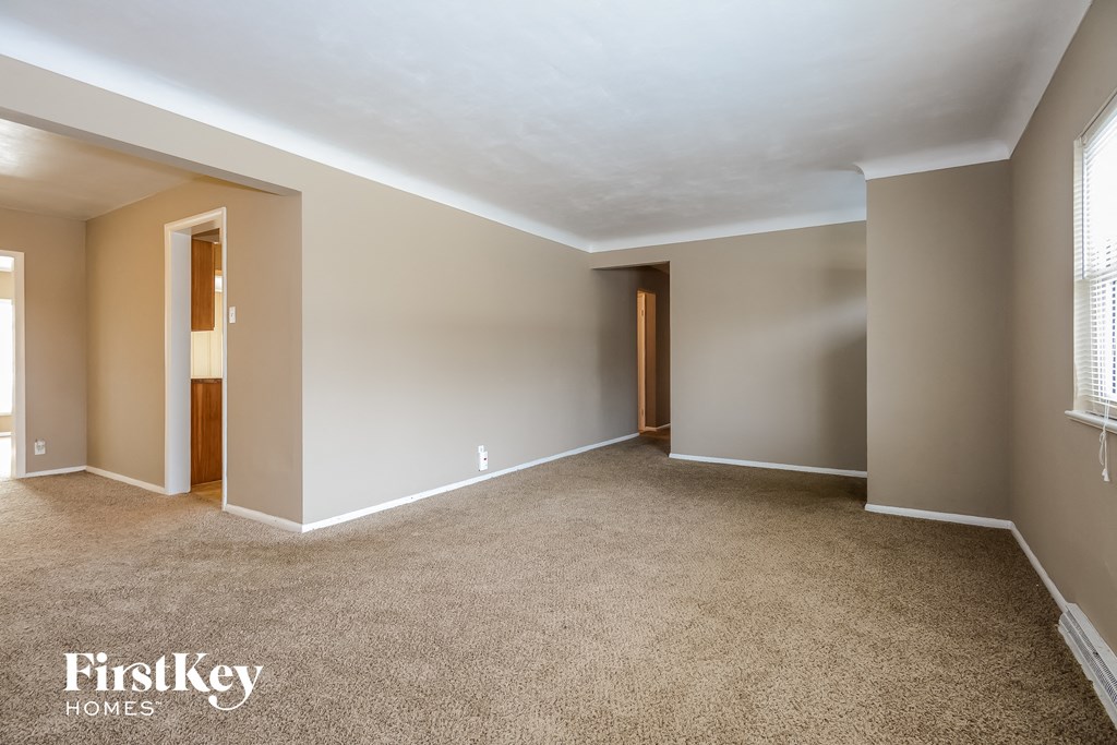 A spacious room with beige walls and carpeted floor.
