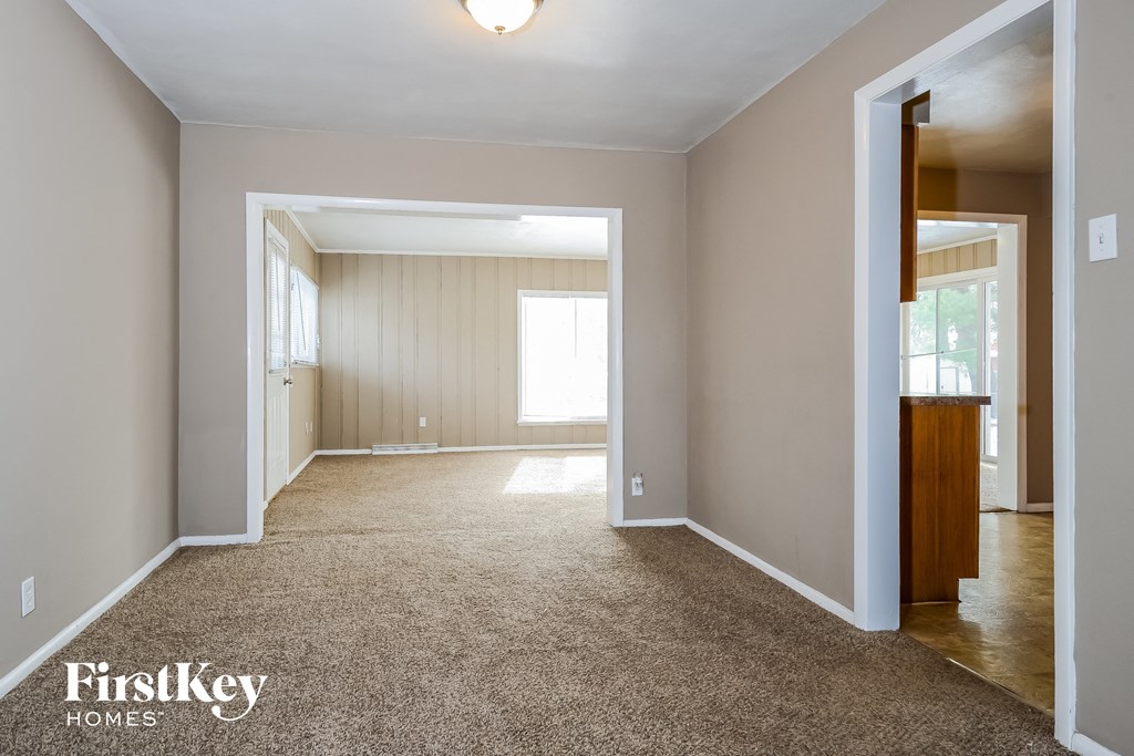 A carpeted room with a doorway leading to another room.