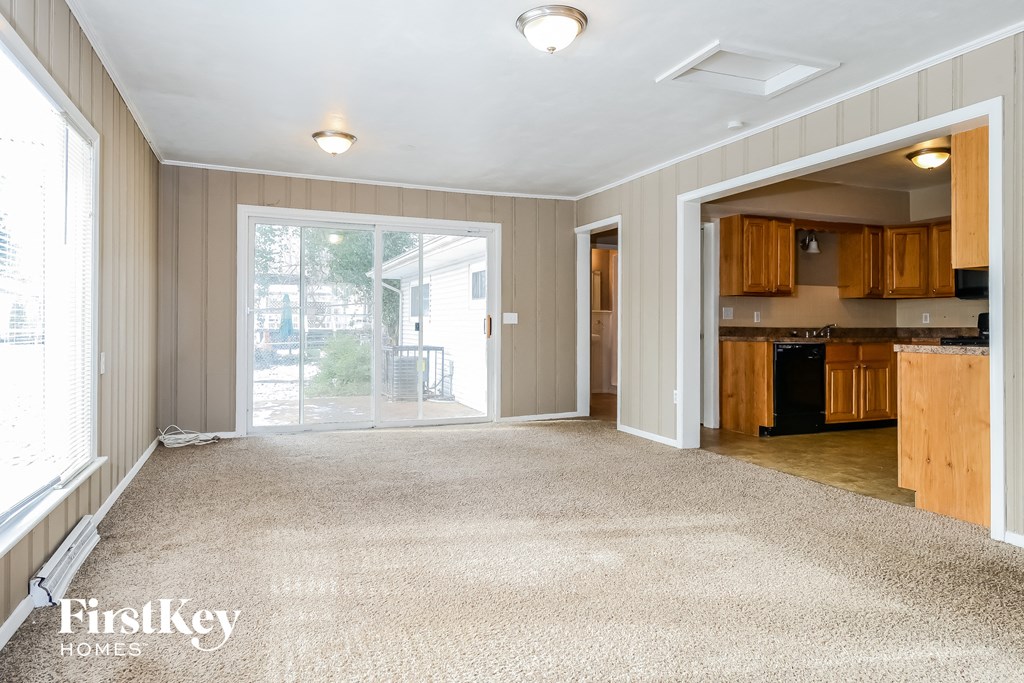A spacious living room with a kitchen area in the background.