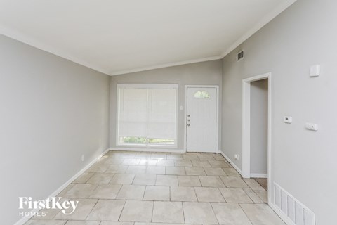 A spacious room with tiled flooring and white walls.