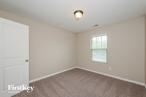 the bedroom of a home with carpet and a window