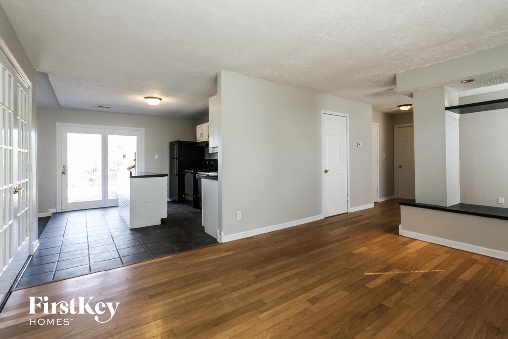 the living room and kitchen of an empty house with wood flooring