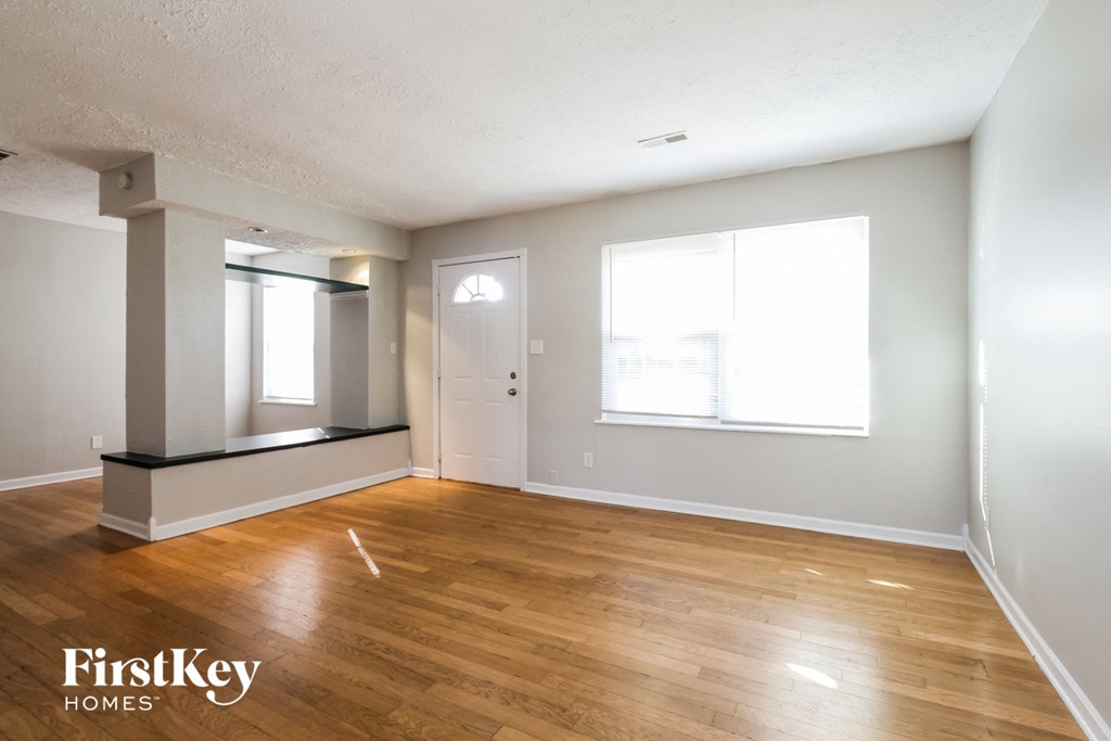 an empty living room with wood floors and a white door