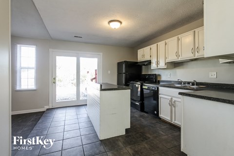 a kitchen with white cabinets and black appliances and a sliding glass door