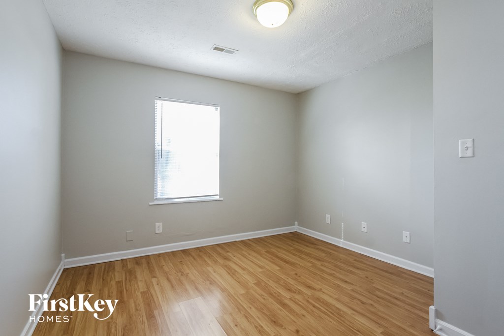 the living room of an empty house with wood floors and a window