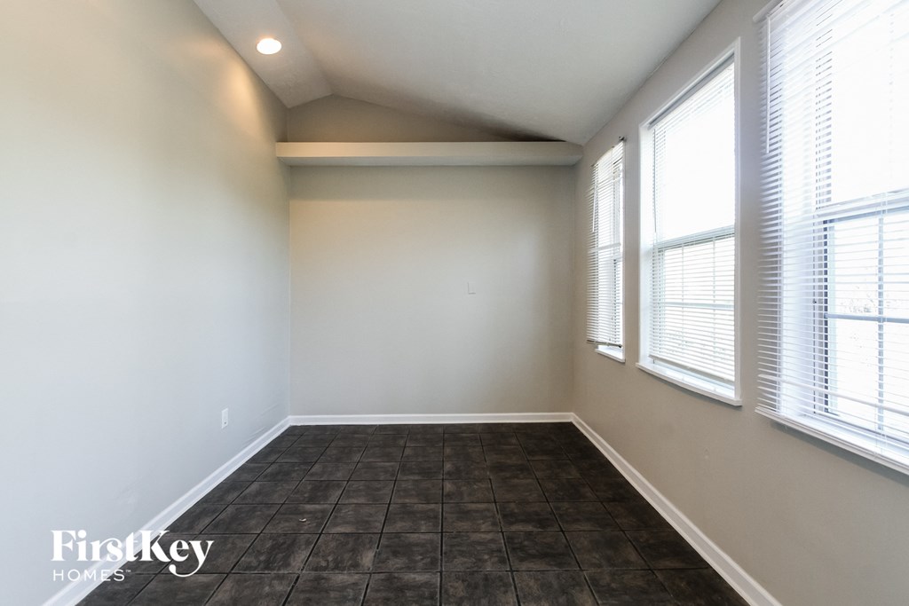 an empty room with three windows and a tiled floor