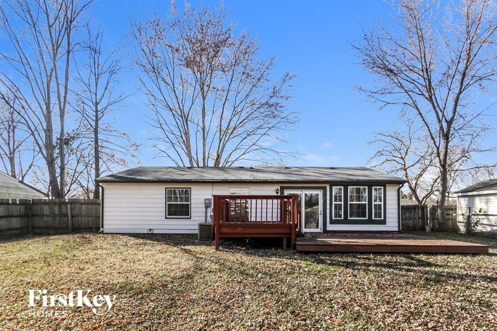 a small white house with a deck in front of a fence