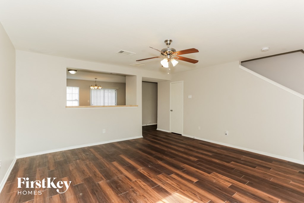 A spacious room with wooden flooring and a ceiling fan.