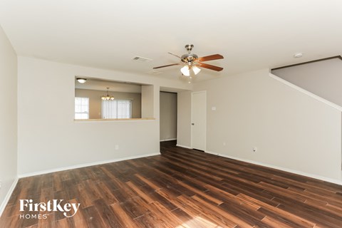 A spacious room with wooden flooring and a ceiling fan.