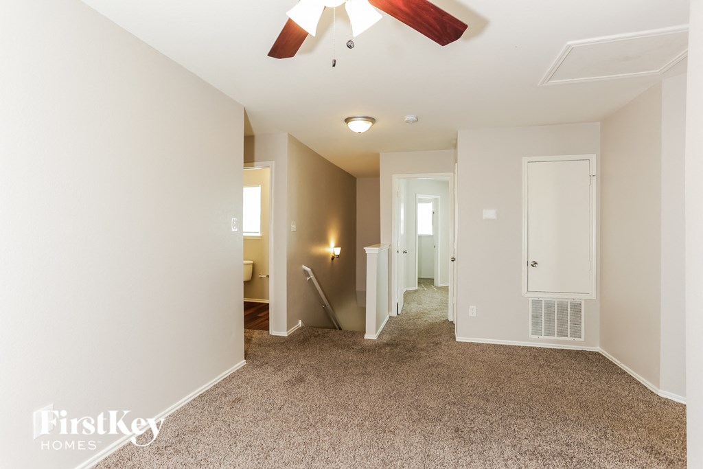 A spacious room with a carpeted floor and a ceiling fan.