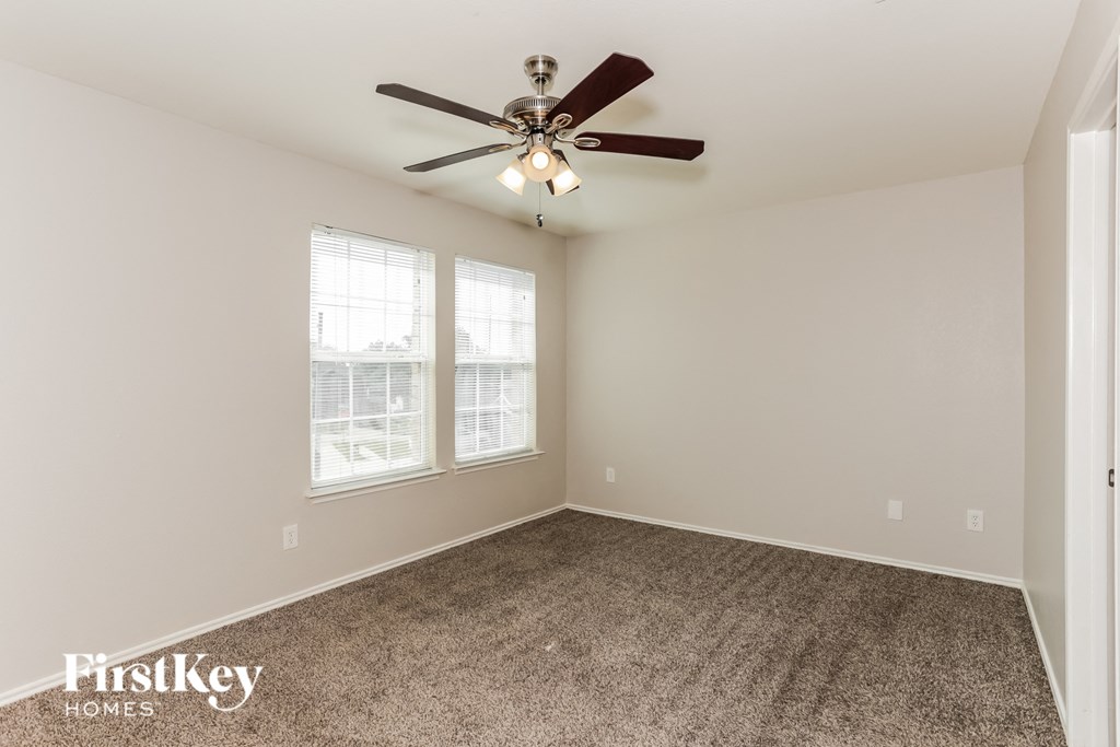 A room with a ceiling fan and carpeted floor.