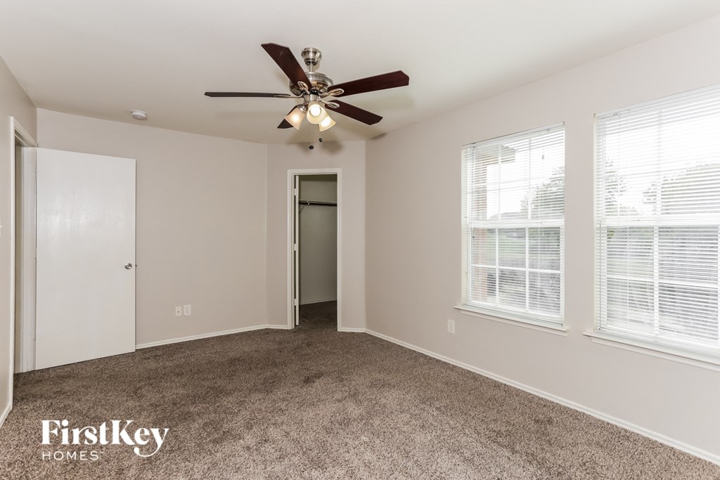 A spacious room with a ceiling fan and carpeted floor.