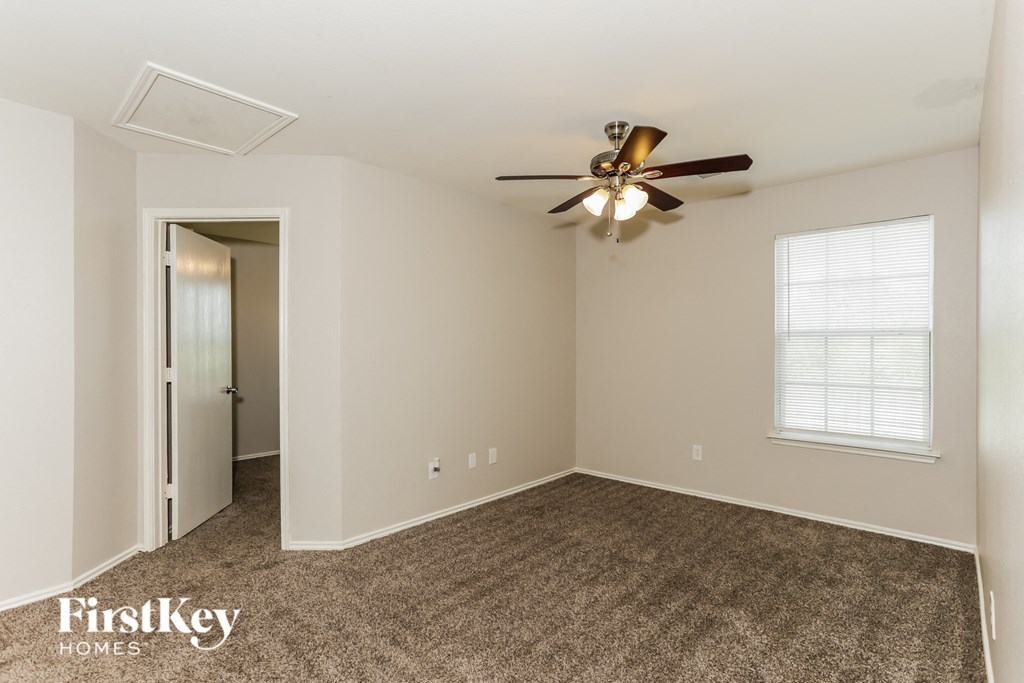 A spacious room with a ceiling fan and a window with blinds.