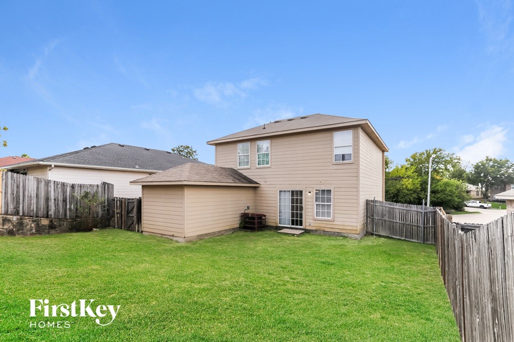 A house with a fence and a lawn in front of it.