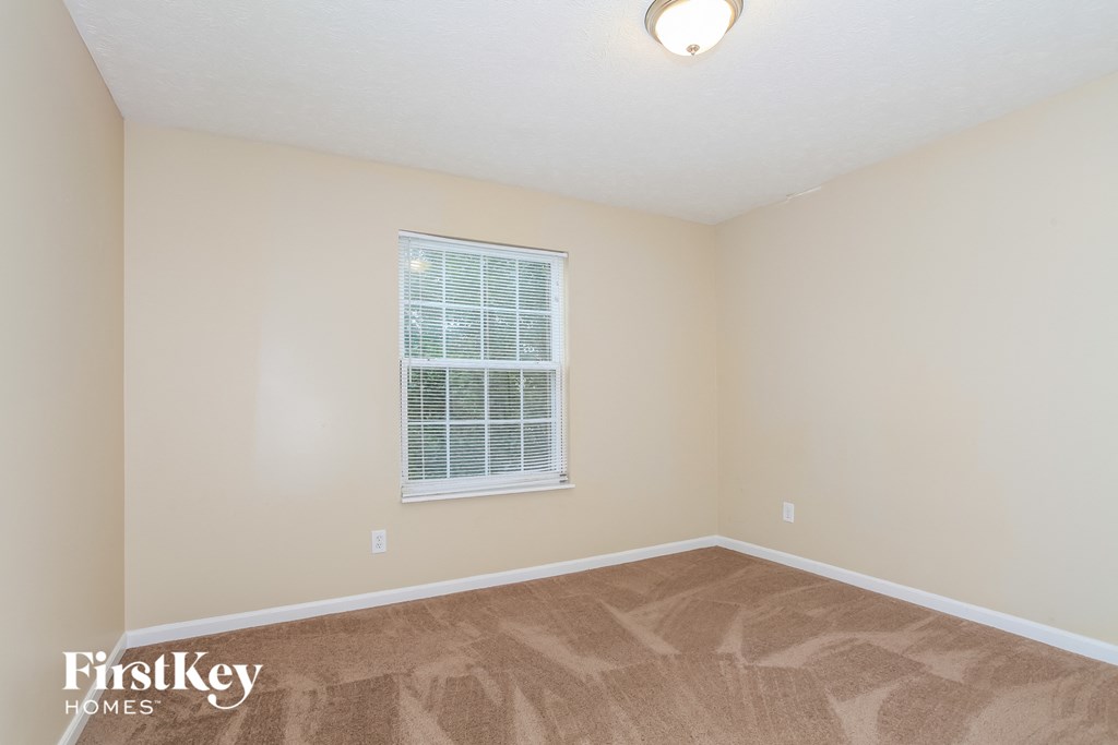 a bedroom with a window and a carpeted floor