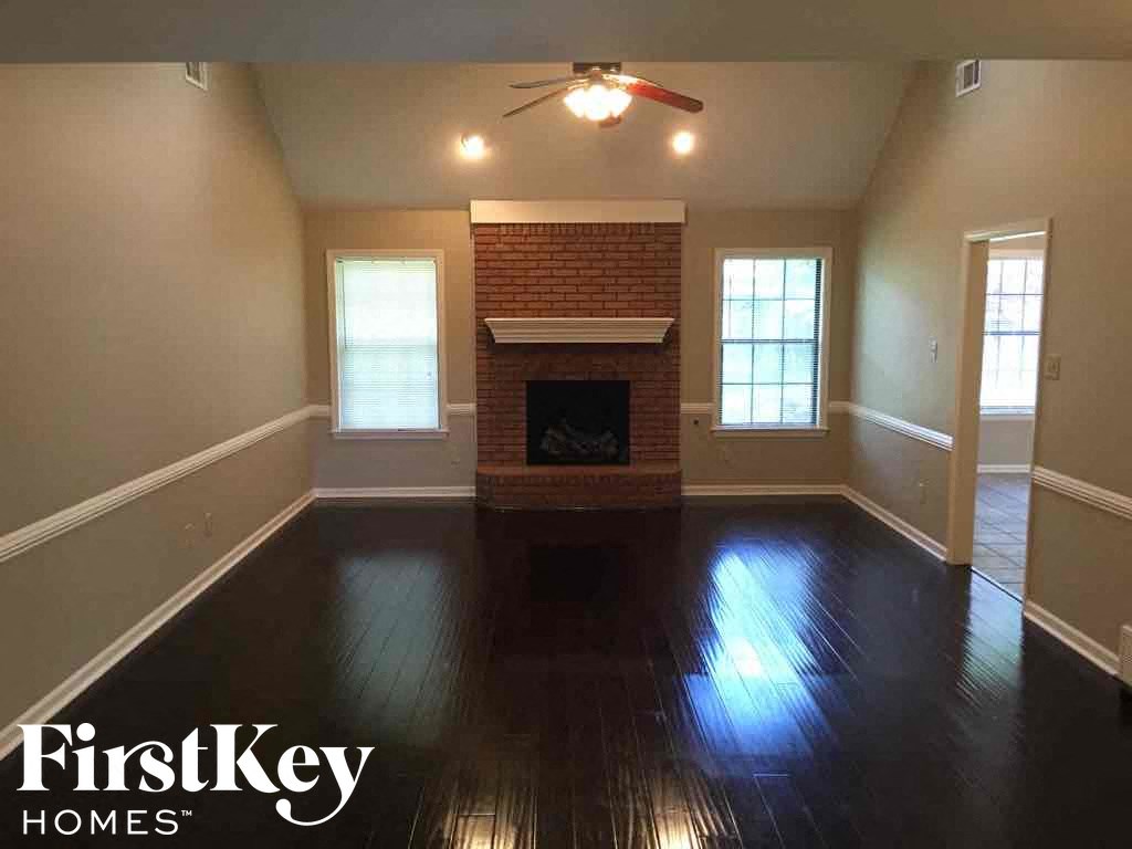 A room with a brick fireplace and wood floors.