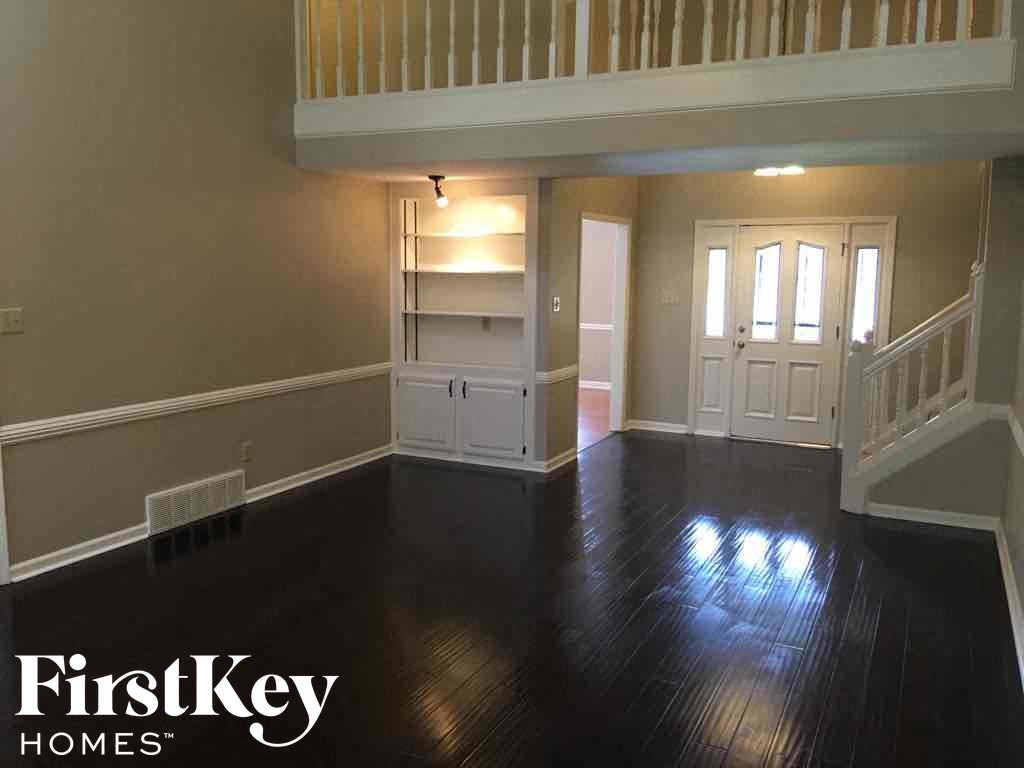A spacious room with wooden floors and a staircase.