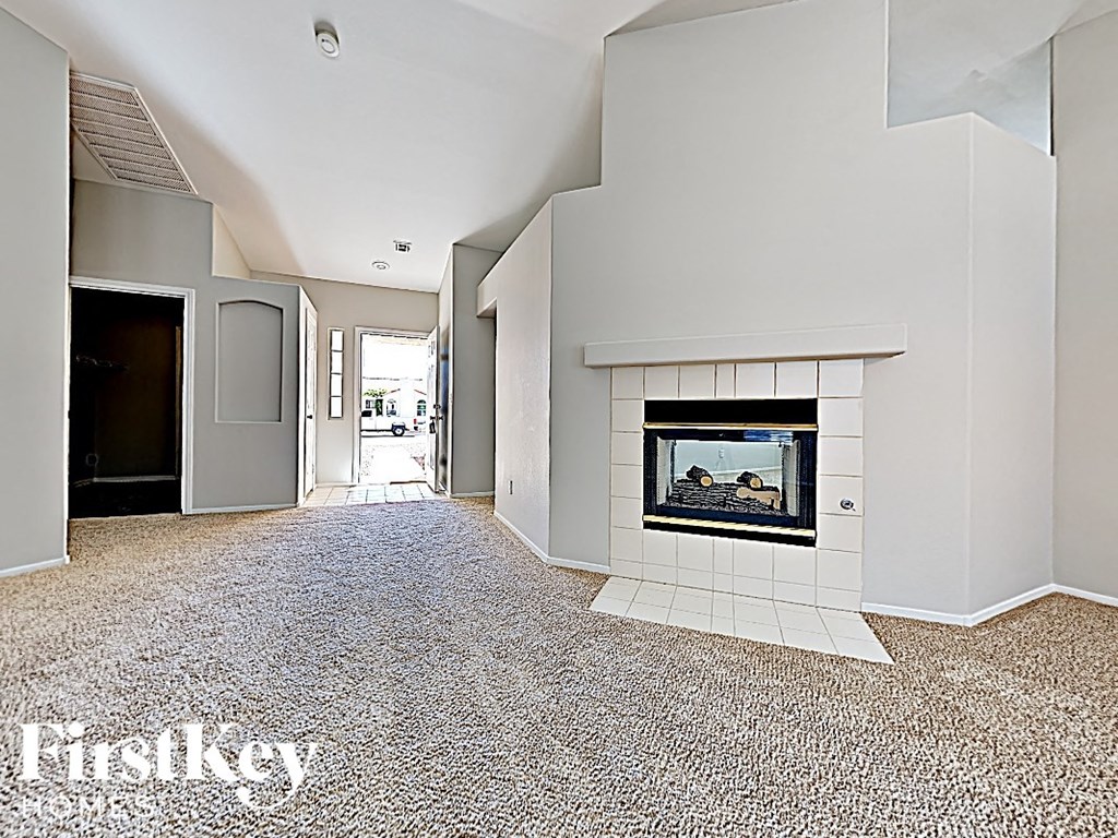 A spacious living room with a fireplace and a carpeted floor.