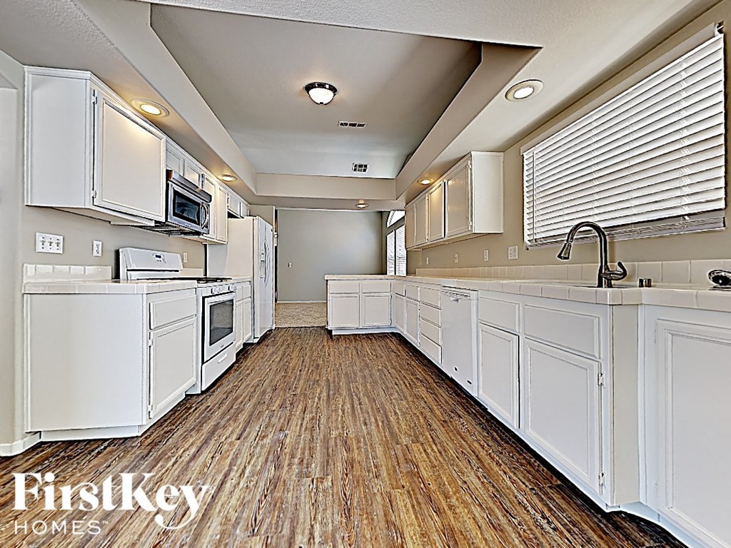 A kitchen with white appliances and cabinets.
