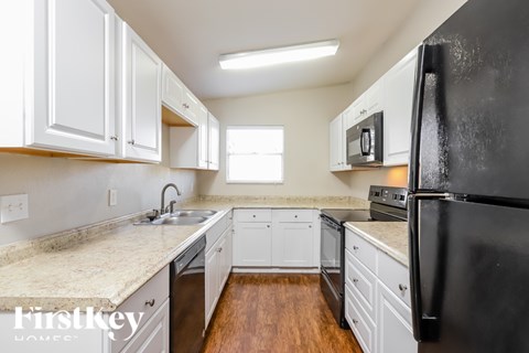 A kitchen with white cabinets and a black refrigerator.